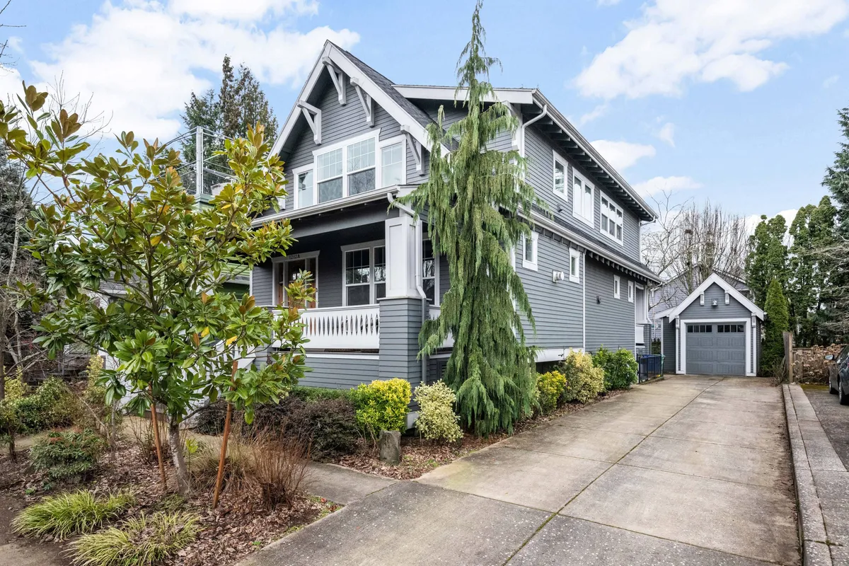 The image showcases the charming exterior of a two-story craftsman home nestled amid lush greenery, with a welcoming porch, spacious garage, and inviting outdoor spaces that hint at relaxation and gatherings. The scene feels warm and inviting, perfect for enjoying morning coffee or sunset barbecues.