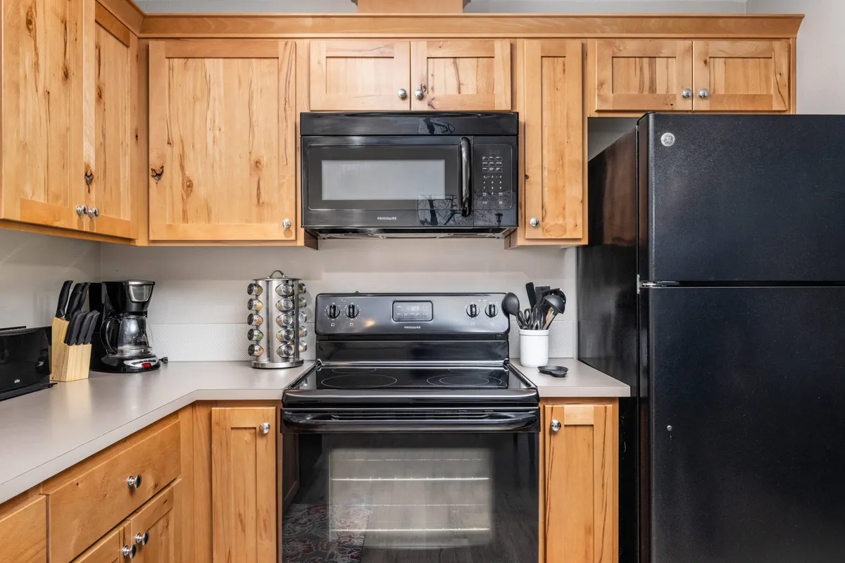 Featuring a similar kitchen angle, this image highlights black appliances, matching wooden cabinetry, and a spacious countertop. The setup suggests both everyday comfort and capability for entertaining, reinforcing the narrative of modern amenities paired with inviting charm.