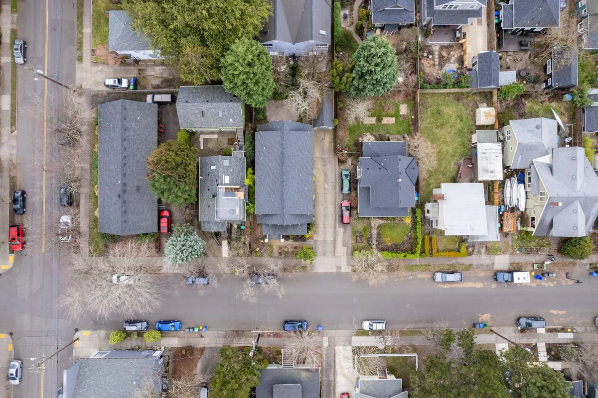 A tranquil exterior scene of a tree-lined neighborhood street with a row of charming houses, surrounded by a leafy canopy. The atmosphere is inviting and walkable, with sidewalks perfect for strolling, walking pets, or heading to nearby cafes and parks.