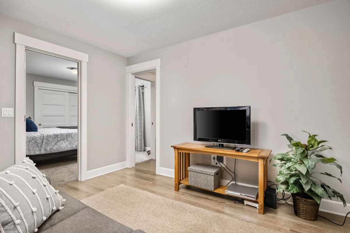 This interior shot looks into the entryway, with a wooden console table, television, indoor plant, and open doorways leading to other rooms. The blend of warm materials and clean finishes hints at both modern comfort and old-world touches, welcoming guests as they step inside.